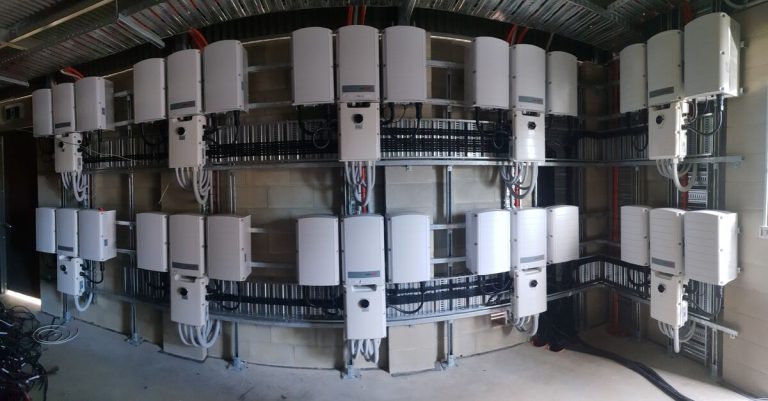 Wall of grid-connect solar inverters wired in a commercial plant room