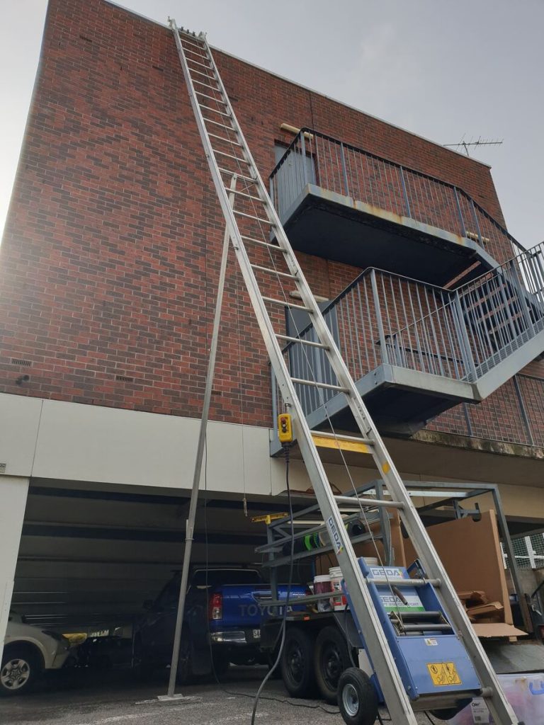 Ladder and material hoist set up against a commercial building