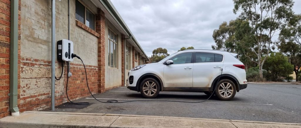 Wall mounted EV charger charging a fleet SUV at a commercial building
