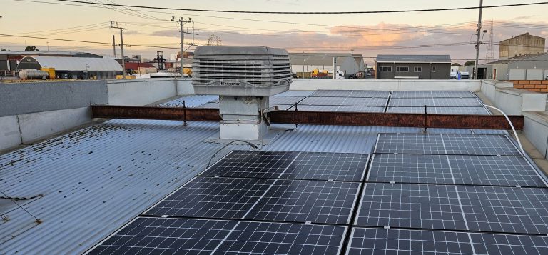 Commercial rooftop solar array at dusk over an industrial area