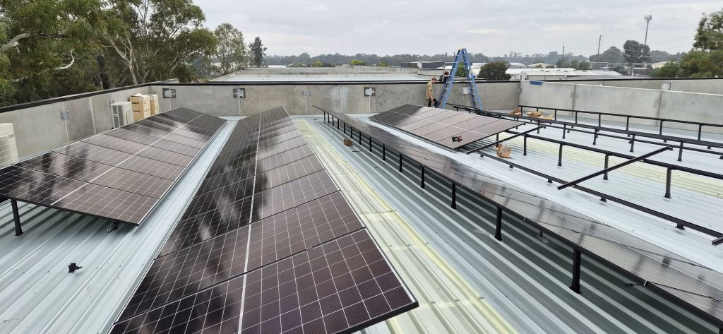 Technician installing solar panels and racking on a commercial rooftop