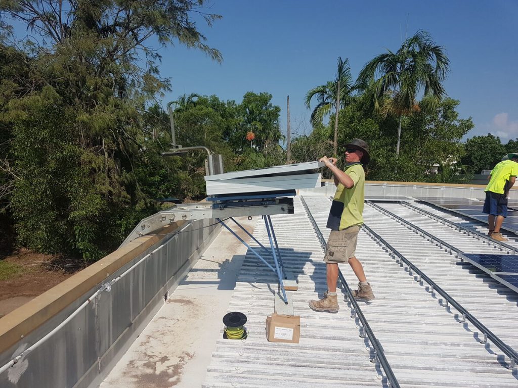 Electrician lifting a solar tilt frame on a commercial roof